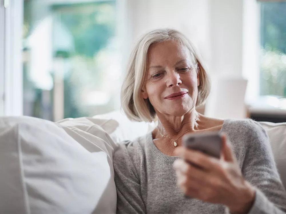 alte Frau auf Sofa mit Smartphone